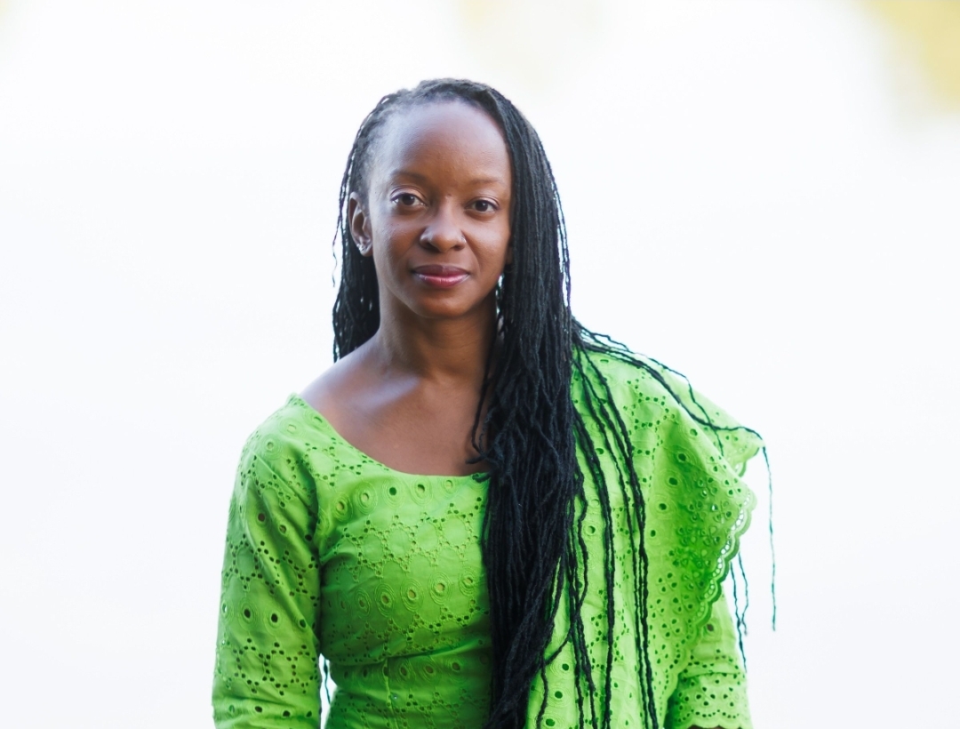 Tamara Williams, a Black woman with long locs, wearing a bright green embroidered blouse and facing the camera with a gentle smile.